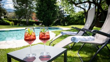 Zwei Aperitifgetränke stehen auf einem Tisch vor dem Pool