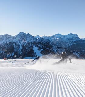 Zwei Skifahrer fahren eine Skipiste am Kronplatz bergab
