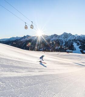 Zwei Skifahrer fahren eine Skipiste am Kronplatz bergab