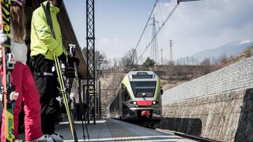 Skifahrer warten am Bahnhof auf den Zug